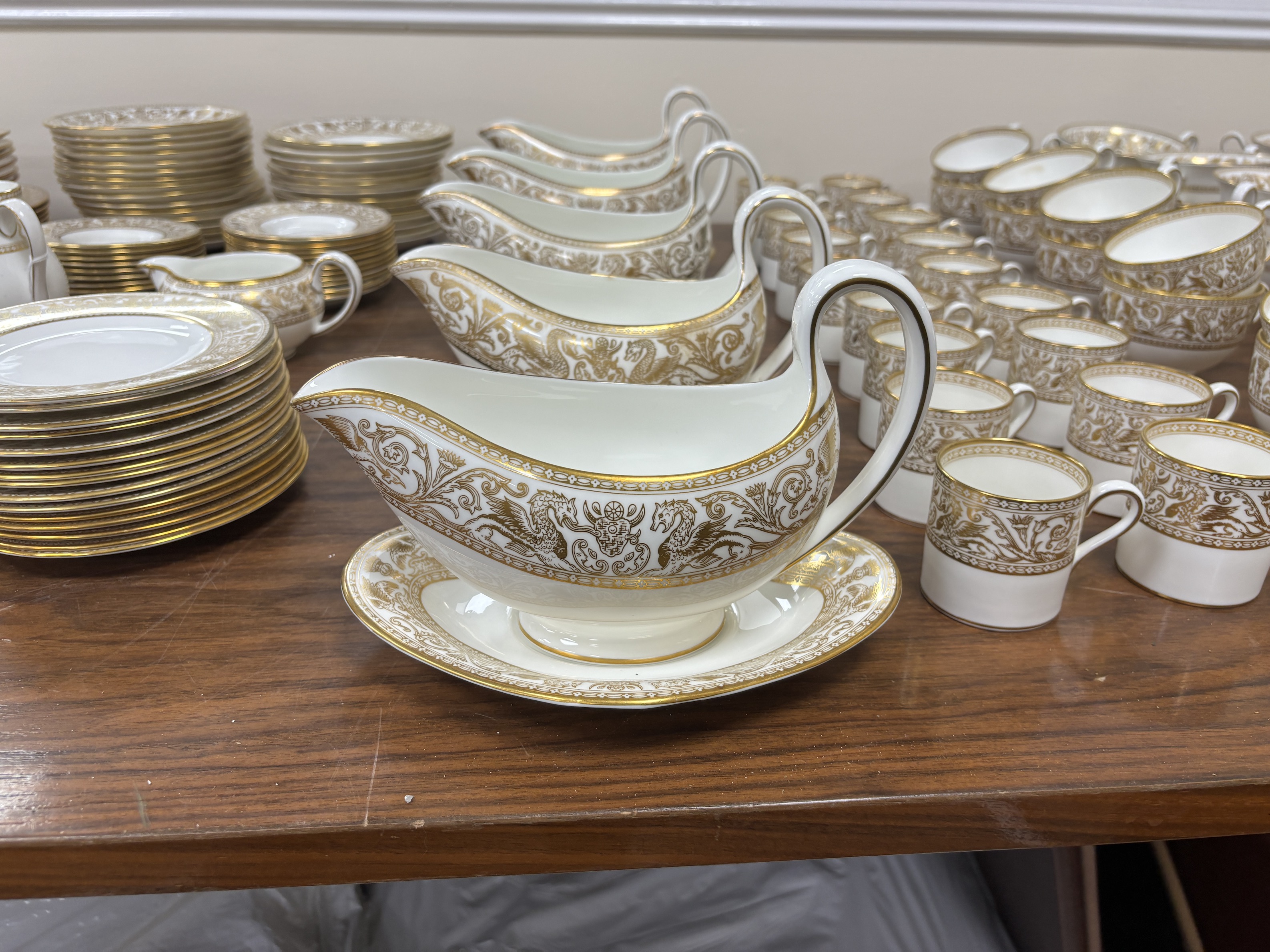 An extensive Wedgwood Gold Florentine dinner service, including 26 dinner plates, 50 side plates, 18 soup bowls with 16 saucers, 6 tea cups and 4 saucers, 6 bowls, 6 large cheese plates, 5 gravy boats and 3 saucers, 3 ve